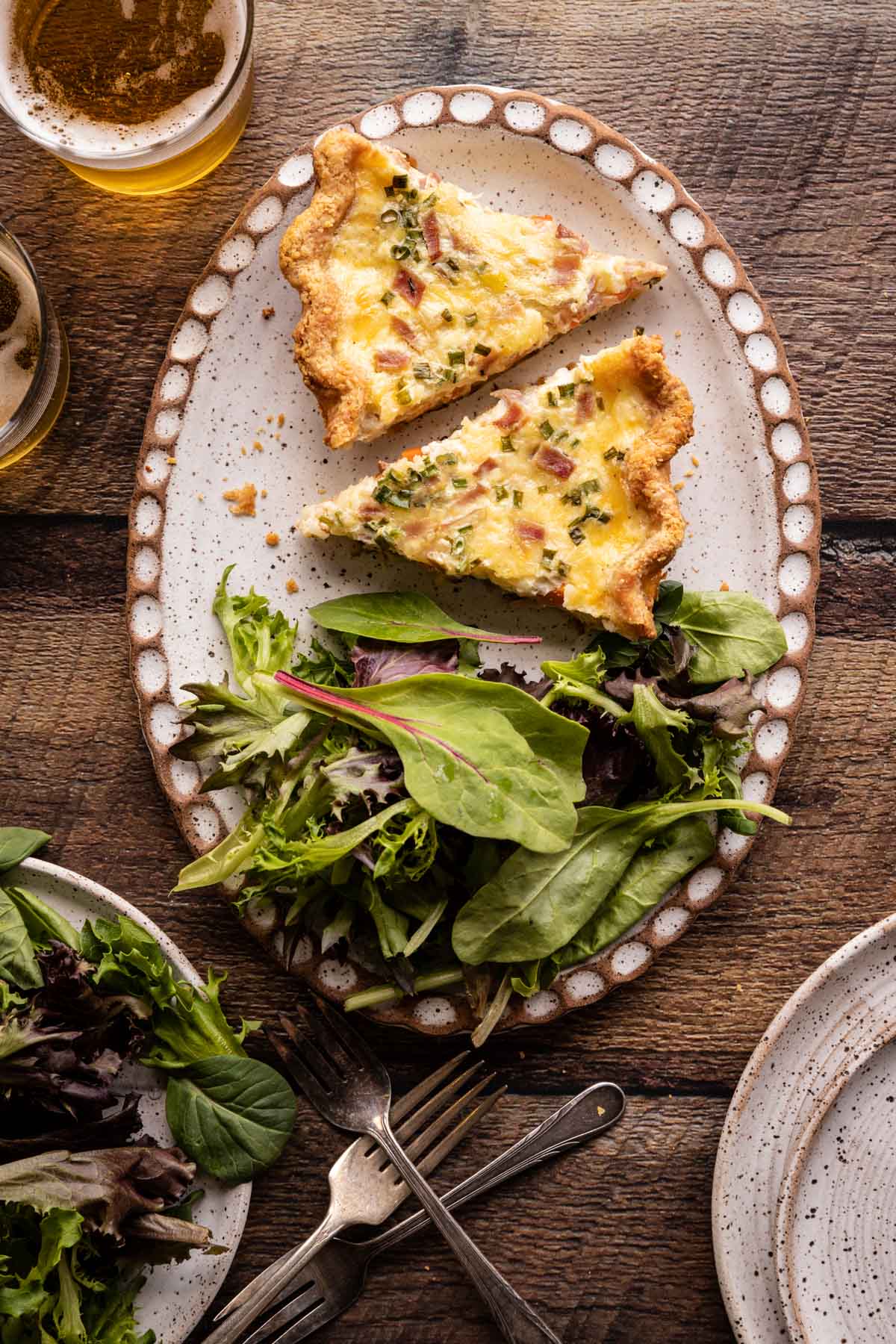 Two slices of quiche on a plate with salad greens