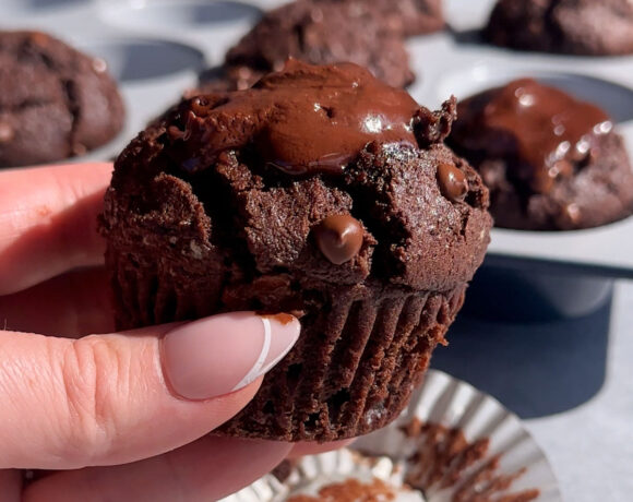 A hand holding an Olympic chocolate muffins with ganache on top